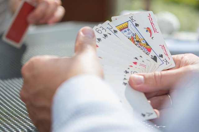 Mann hält Spielkarten aufgefächert in den Händen 